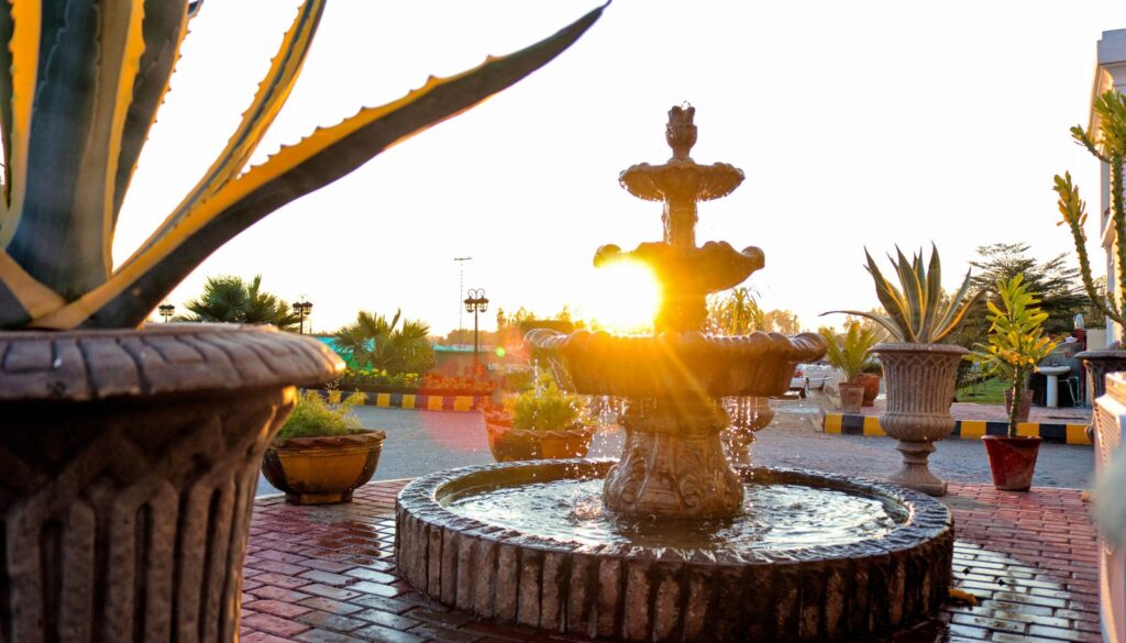 A fountain in a landscaped garden at sunset