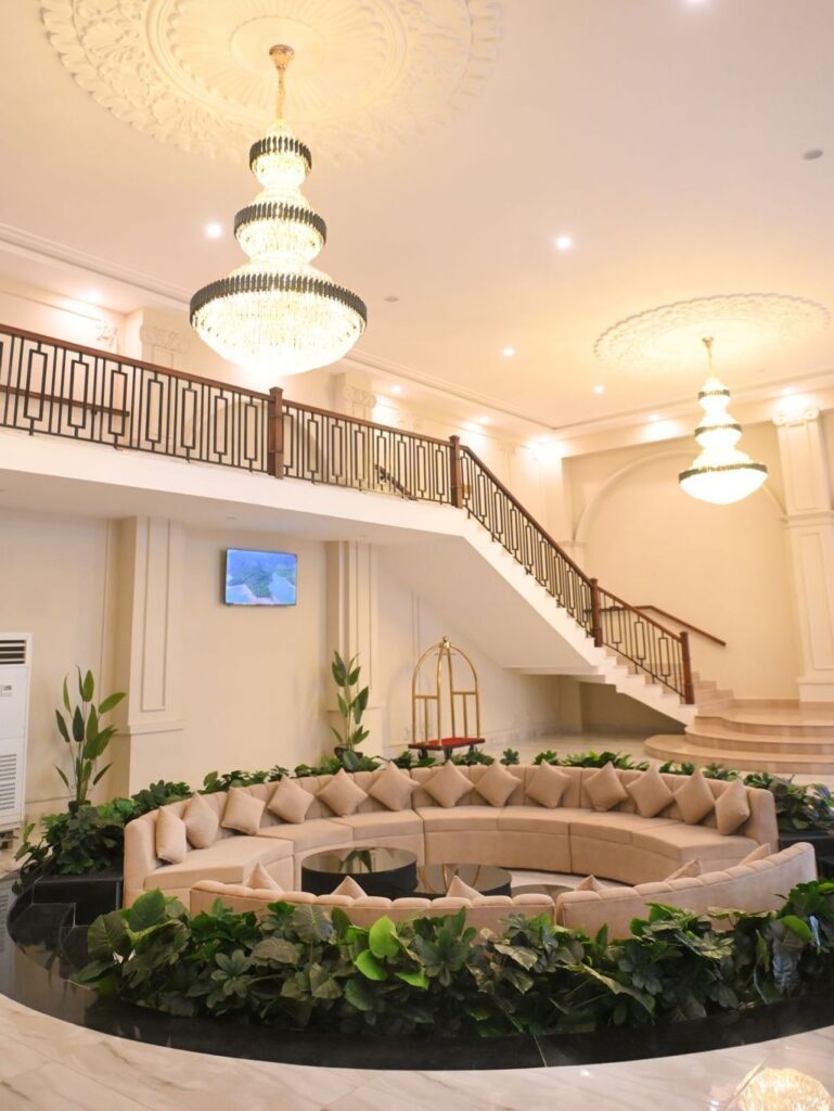 The Alhamra Hotel lobby with chandeliers and a curved staircase